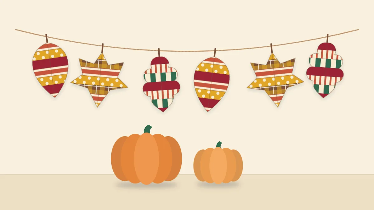 A garland of paper leaves covered in washi tape stripes in rust, mustard and deep red, hanging on twine above two small pumpkins