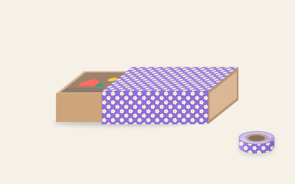 A small sliding drawer box with its sleeve wrapped in patterned washi tape and the drawer partly open