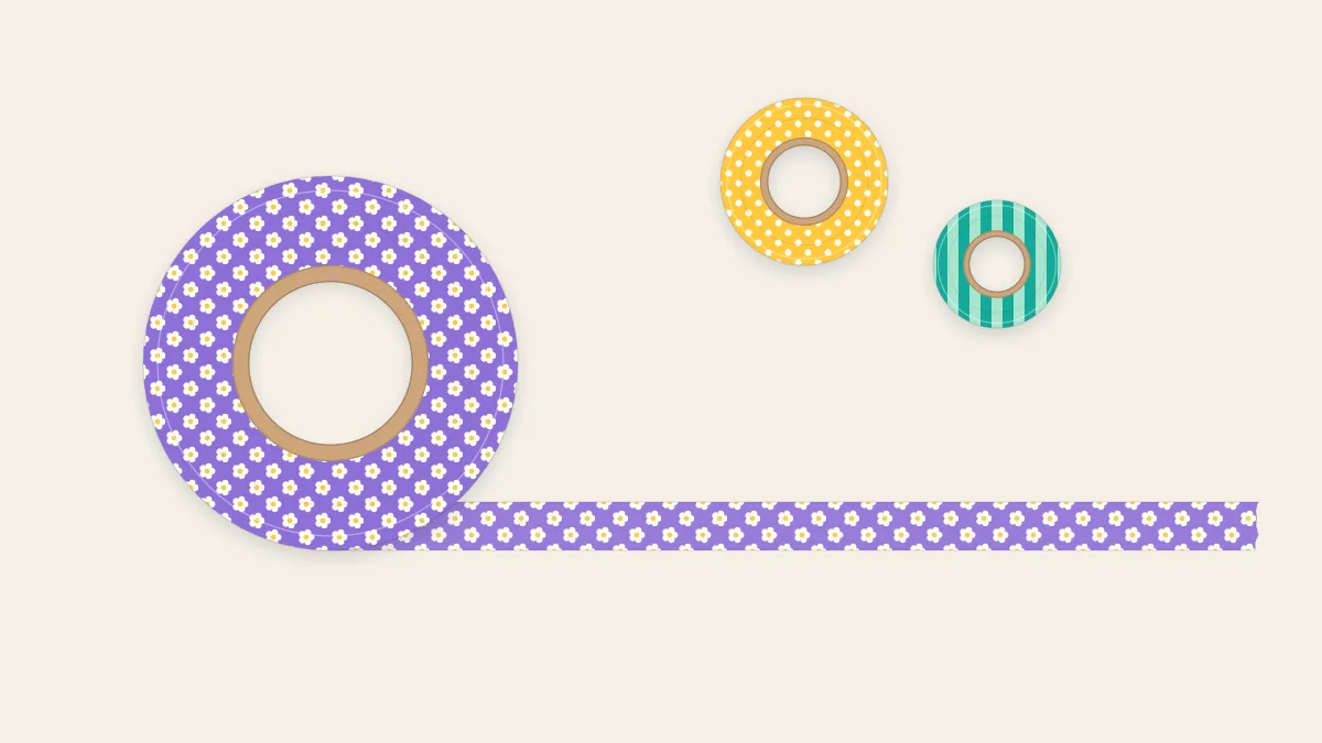 A large washi tape roll with a patterned strip unrolling across a desk and two smaller rolls behind it